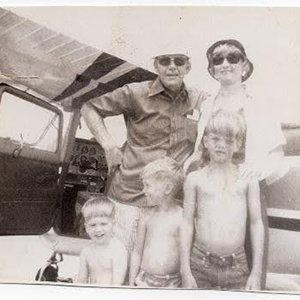 A black and white family photo by an airplane